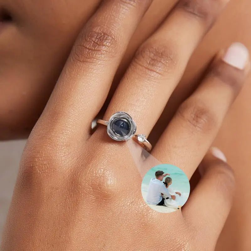 Anel feminino de prata com foto personalizada em close no dedo, mostrando a pedra central com imagem interna do casal.
