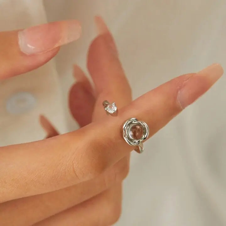 Close de anel feminino de prata personalizado no dedo, com pedra central em formato de rosa e acabamento delicado.