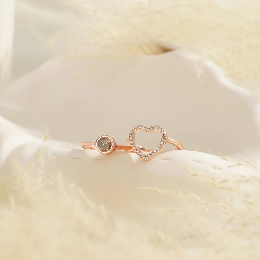 Anel feminino rosé com coração cravejado e espaço central para foto, exibido em fundo claro.