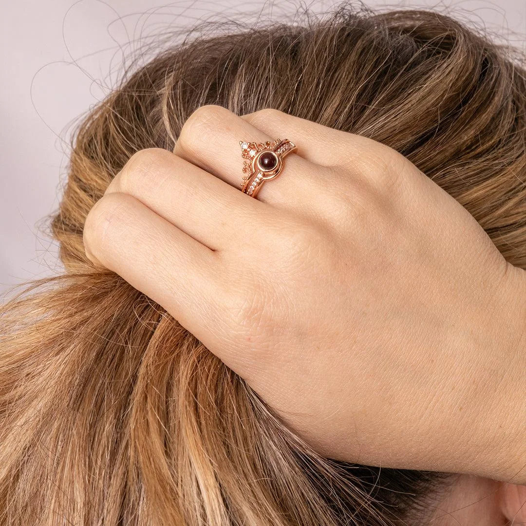 Anel rosé personalizado usado na mão, com detalhe delicado da pedra central e visual elegante em close na mão próxima ao cabelo.