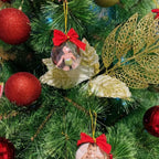 Bola de Natal personalizada com foto de criança pendurada na árvore, ao lado de enfeites vermelhos e dourados.