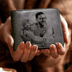 Carteira masculina de couro cinza personalizada com foto gravada na frente, em close, sendo segurada nas mãos.
