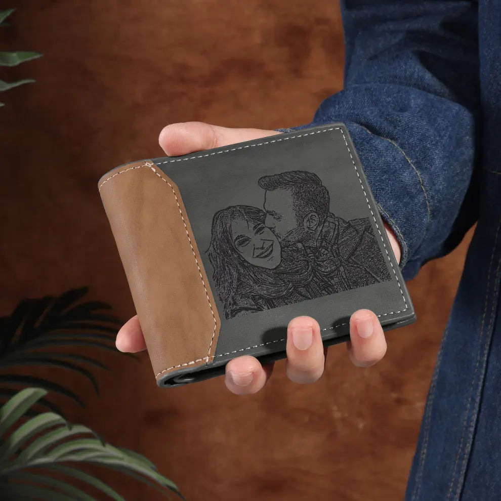 Carteira masculina de couro cinza personalizada com foto  gravada de casal sendo segurada na mão, mostrando o acabamento frontal da gravação e lateral costurada a mão.
