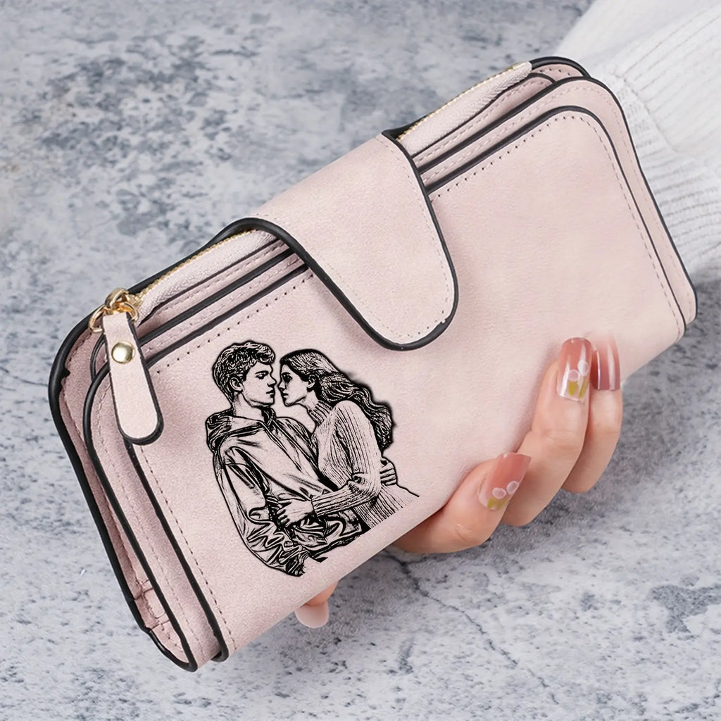 Carteira feminina de couro rosa personalizada sendo segurada na mão, com detalhe de casal na frente.