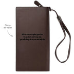 Carteira marrom personalizada vista pelo verso com frase romântica de exemplo gravada e alça de mão presa na parte superior.