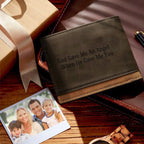Carteira masculina de couro marrom com gravação personalizada, posicionada sobre mesa com caixa de presente e fotografia ao lado.