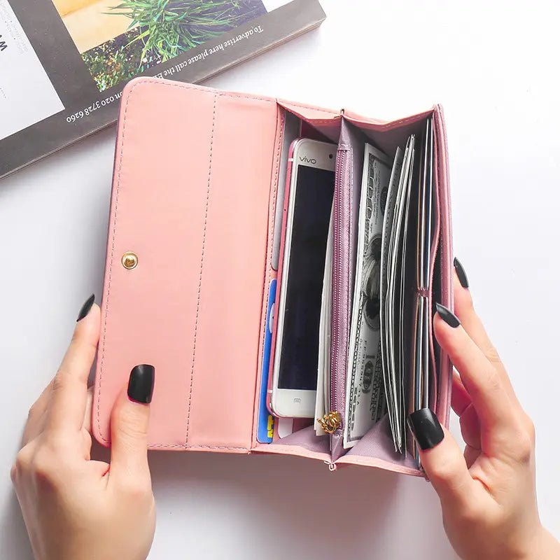 Carteira feminina rosa personalizada aberta, com compartimentos para cartões, celular e dinheiro em uso.