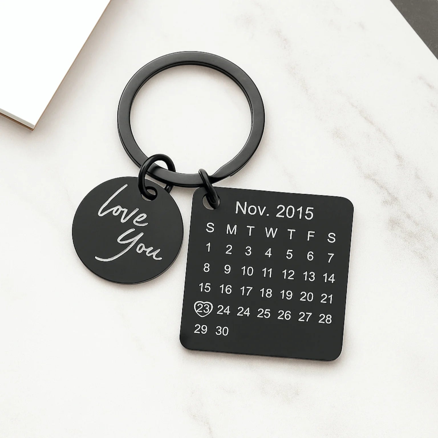 Chaveiro preto personalizado com pingente escrito love you e placa quadrada com calendário e data destacada.