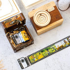 Chaveiro de câmera retrô com filme fotográfico personalizado exibido ao lado de uma caixa decorativa.