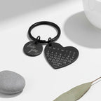 Chaveiro de coração preto personalizado posicionado sobre mesa branca com decoração minimalista ao fundo.