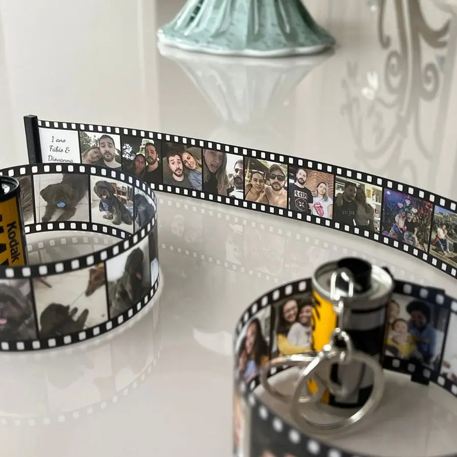 Chaveiro personalizado de câmera retrô com fita de filme exibindo várias fotos impressas.