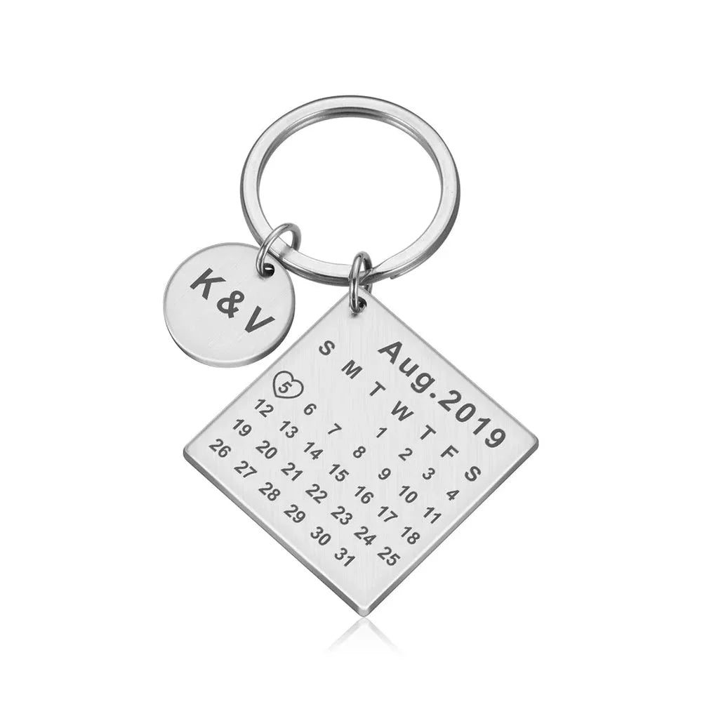 Chaveiro prata personalizado com placa quadrada em formato de calendário e pingente circular com iniciais gravadas.