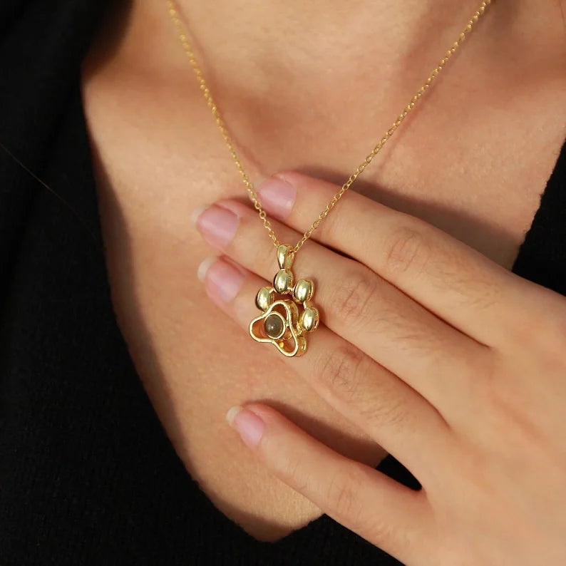 Colar personalizado dourado de patinha sendo usado no pescoço de mulher, com close do pingente de patinha em destaque.