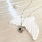 Colar de prata personalizado com pingente de patinha e foto pet sobre base decorativa clara.
