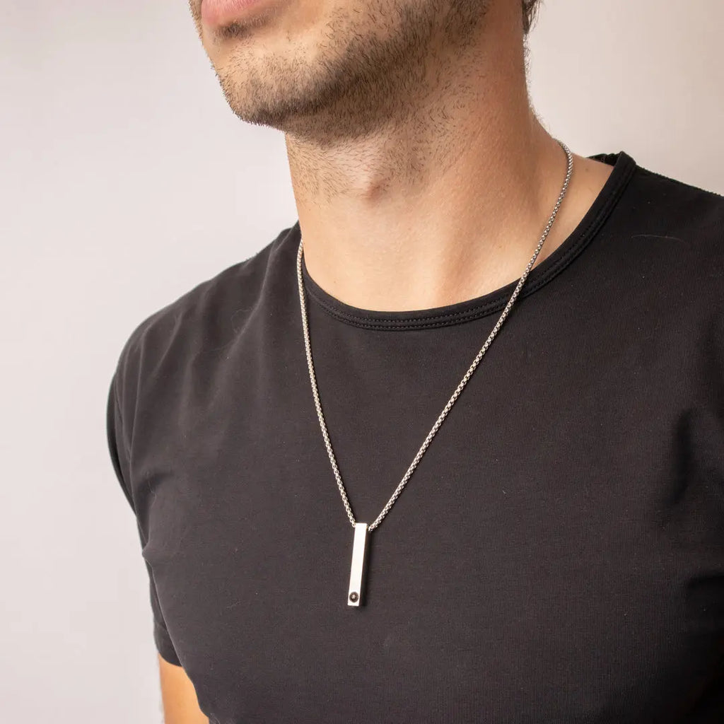 Colar de prata personalizado com pingente retangular usado com camiseta preta, mostrando o modelo no corpo masculino.