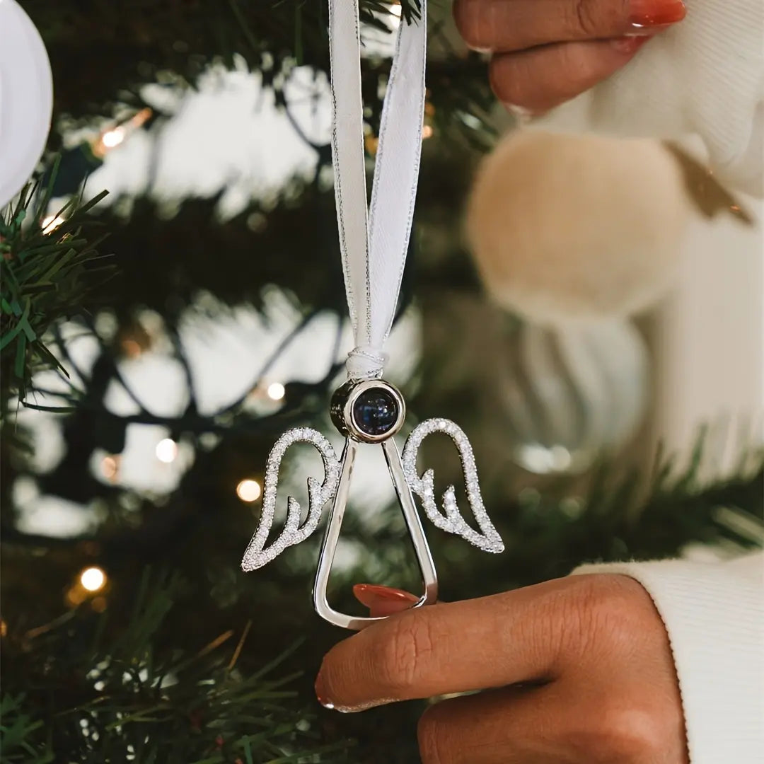 Enfeite de natal em formato de anjo personalizado pendurado na arvore, com acabamento metalico, asas detalhadas e fita branca para suspensao.