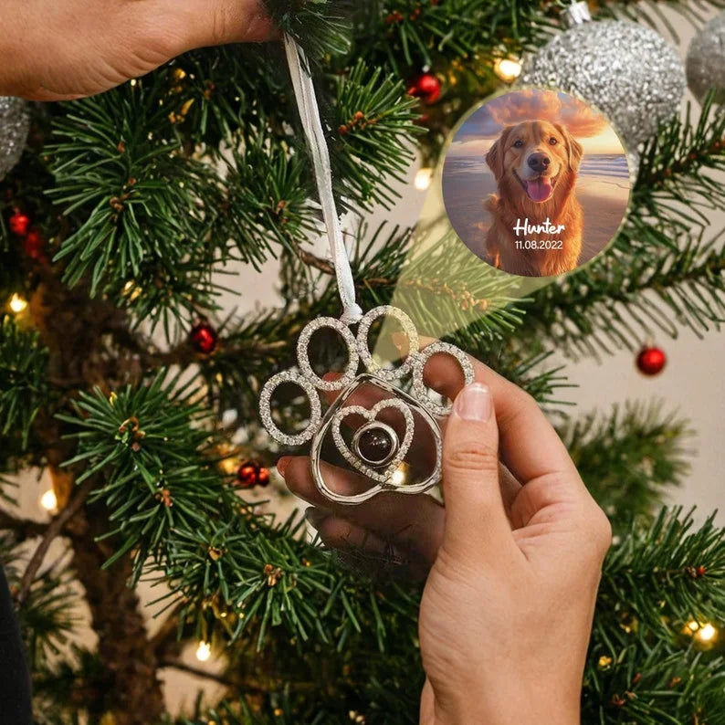 Enfeite de árvore de Natal em formato de pata de pet com foto personalizada  no centro de exemplo pendurado na árvore durante a decoração.