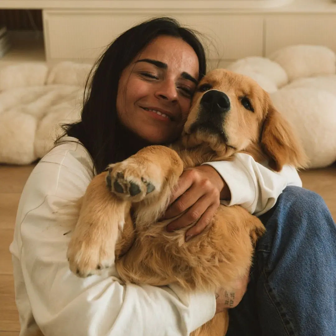 Pessoa abraçando um cachorro em ambiente interno, ilustrando o uso de um acessório personalizado para pet com foto especial.